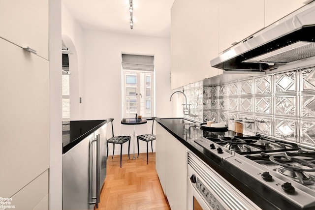 165 W 20th St Unit 6F, New York City, NY 10011 - kitchen featuring exhaust hood, a sink, stainless steel gas stovetop, dark countertops, and tasteful backsplash
