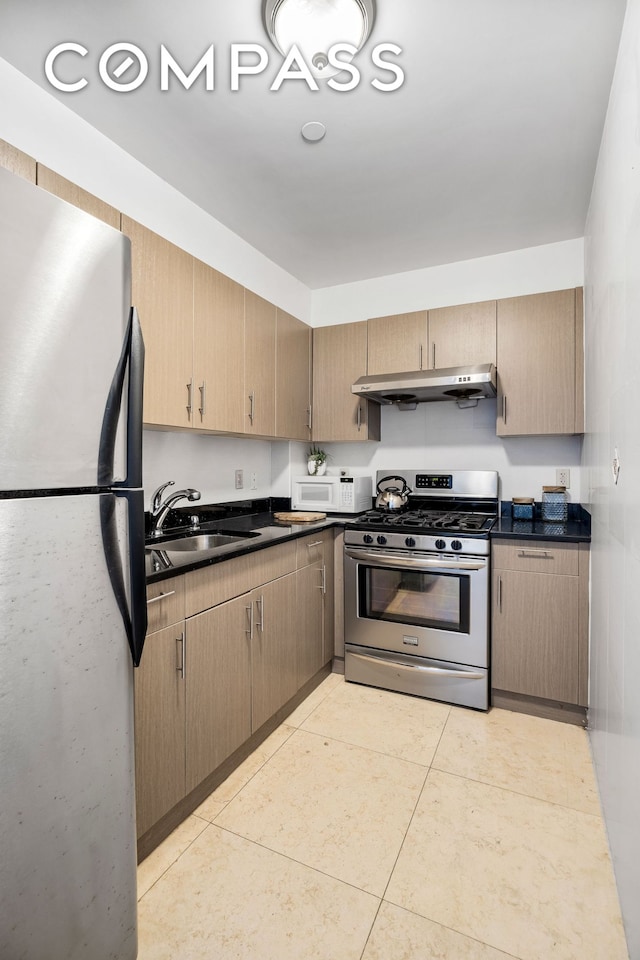 228 Bushwick Ave Unit 3B, New York City, NY 11206 - kitchen with appliances with stainless steel finishes, under cabinet range hood, a sink, dark countertops, and light tile patterned flooring