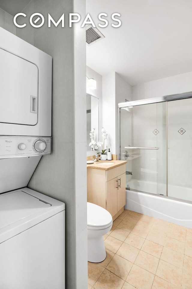 228 Bushwick Ave Unit 3B, New York City, NY 11206 - bathroom with estacked washer and dryer, vanity, tile patterned floors, and combined bath / shower with glass door