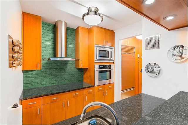 245 E 93rd St Unit 5Lm, New York City, NY 10128 - kitchen with built in appliances, wall chimney exhaust hood, backsplash, dark stone countertops, and brown cabinets
