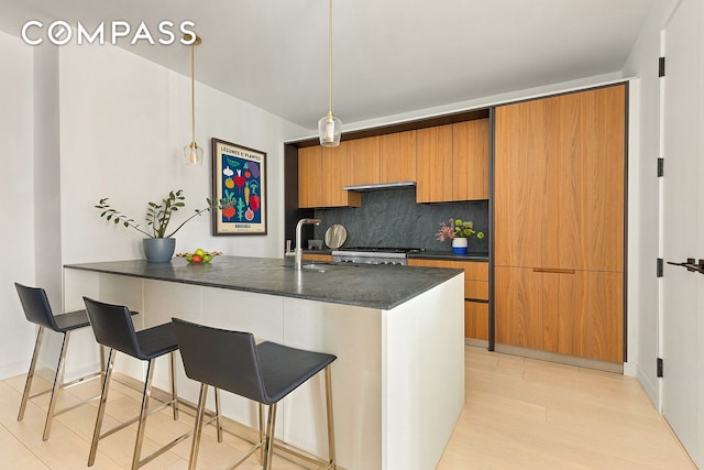 856 Washington Ave Unit 6A, New York City, NY 11238 - kitchen with backsplash, brown cabinetry, a kitchen breakfast bar, stove, and decorative light fixtures