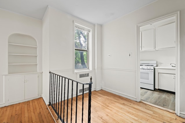 601 E 19th St Unit 3O, New York City, NY 11226 - hallway with light wood-type flooring, radiator heating unit, an upstairs landing, and ornamental molding