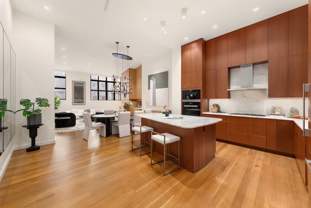 247 W 12th Street Lofta, New York City, NY 10014 - kitchen featuring modern cabinets, wall chimney exhaust hood, a kitchen island, cooktop, and light wood finished floors