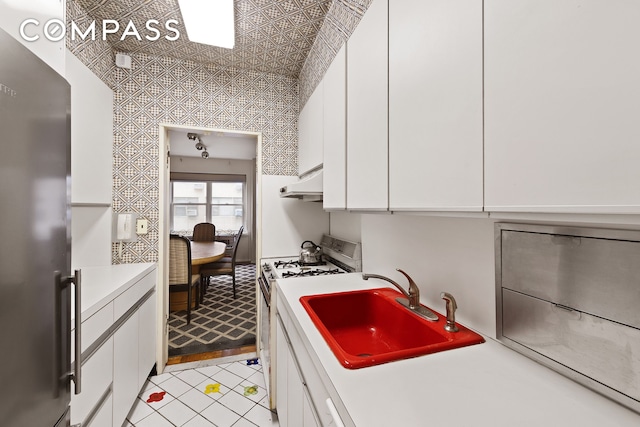 1025 5th Ave Unit 8Gs, New York City, NY 10028 - kitchen featuring freestanding refrigerator, white gas stove, a sink, light countertops, and under cabinet range hood