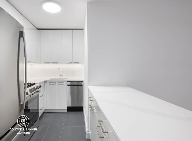 235 E 87th St Unit 7E, New York City, NY 10128 - kitchen featuring stainless steel appliances, a sink, white cabinetry, light countertops, and dark tile patterned flooring
