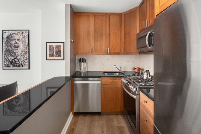 200 W 79th St Unit 9J, New York City, NY 10024 - kitchen featuring appliances with stainless steel finishes, light wood-type flooring, tasteful backsplash, and brown cabinetry