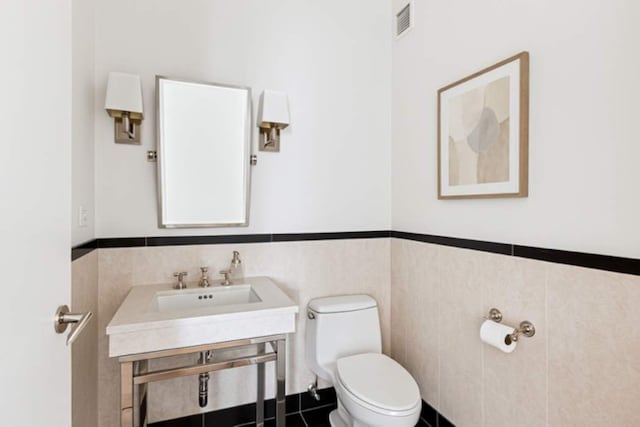 151 E 58th St Unit 42C, New York City, NY 10022 - half bath with toilet, a wainscoted wall, a sink, and tile walls
