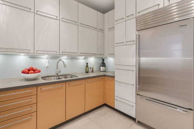 151 E 58th St Unit 42C, New York City, NY 10022 - kitchen with built in refrigerator, a sink, light tile patterned floors, and white cabinetry