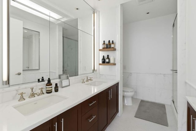 151 E 58th St Unit 42C, New York City, NY 10022 - full bathroom featuring double vanity, a stall shower, toilet, wainscoting, and tile walls