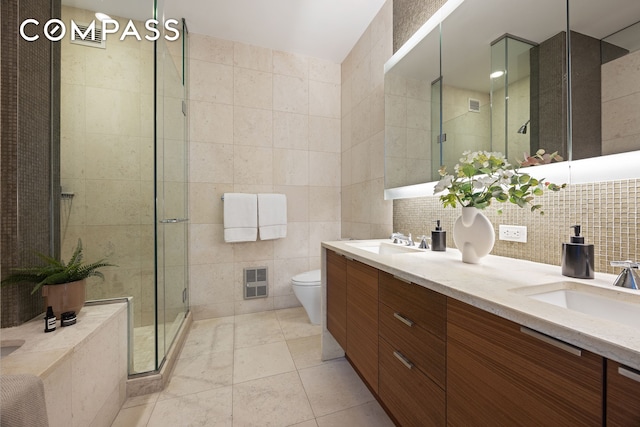 70 Little W St Unit 7L, New York City, NY 10004 - bathroom featuring tile walls, double vanity, a shower stall, toilet, and tile patterned floors