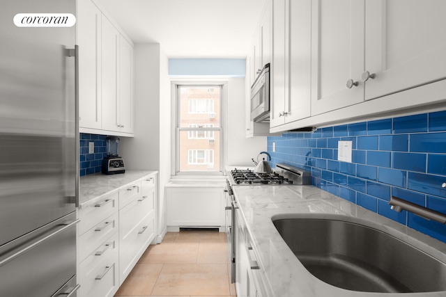 75 E End Ave Unit 6D, New York City, NY 10028 - kitchen featuring stainless steel appliances, tasteful backsplash, light stone counters, and white cabinetry