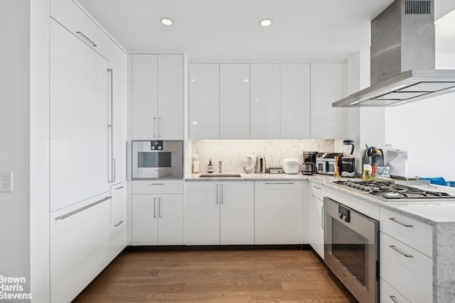 460 W 42nd St Unit 58G, New York City, NY 10036 - kitchen with wall chimney range hood, stainless steel appliances, modern cabinets, white cabinetry, and wood finished floors