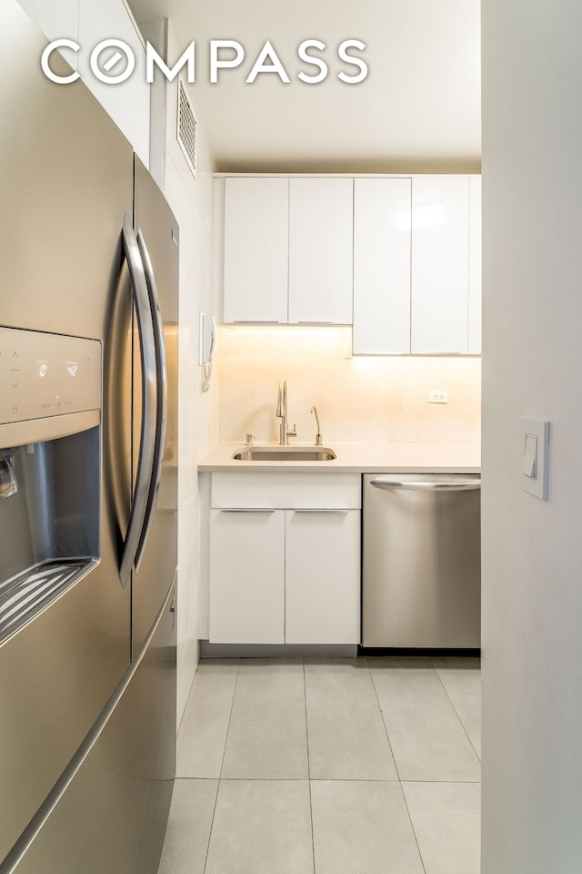 530 E 72nd St Unit 7C, New York City, NY 10021 - kitchen with stainless steel appliances, white cabinetry, light tile patterned floors, light countertops, and modern cabinets