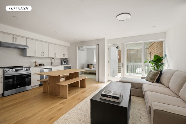 291 6th Ave Unit 1, New York City, NY 11215 - kitchen with appliances with stainless steel finishes, open floor plan, under cabinet range hood, light wood-style flooring, and white cabinets