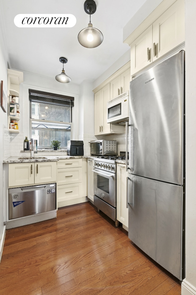333 E 43rd St Unit 511, New York City, NY 10017 - kitchen featuring appliances with stainless steel finishes, tasteful backsplash, light stone counters, decorative light fixtures, and wood finished floors