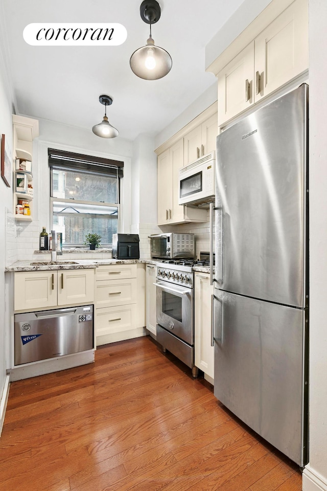333 E 43rd St Unit 511, New York City, NY 10017 - kitchen with appliances with stainless steel finishes, backsplash, light stone countertops, a warming drawer, and light wood finished floors
