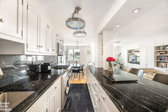 340 E 80th St Unit 17F, New York City, NY 10075 - kitchen featuring stainless steel microwave, white cabinets, washer / dryer, dark stone countertops, and recessed lighting