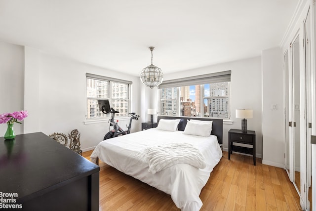 340 E 80th St Unit 17F, New York City, NY 10075 - bedroom featuring baseboards, a chandelier, and light wood-style flooring