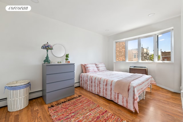46-12 161st St Unit 3B, New York City, NY 11358 - bedroom featuring wood finished floors, baseboards, and a baseboard heating unit