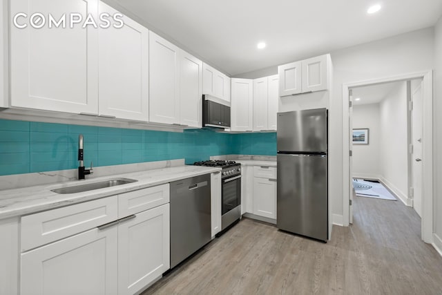 1604 Lexington Ave, New York City, NY 10029 - kitchen featuring stainless steel appliances, a sink, white cabinets, decorative backsplash, and recessed lighting