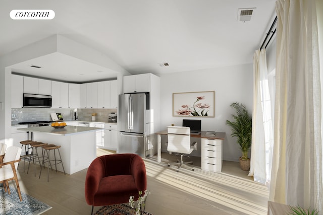 3-17 Endeavor Pl Unit C, New York City, NY 11356 - kitchen with stainless steel appliances, tasteful backsplash, a breakfast bar area, a kitchen island, and a desk