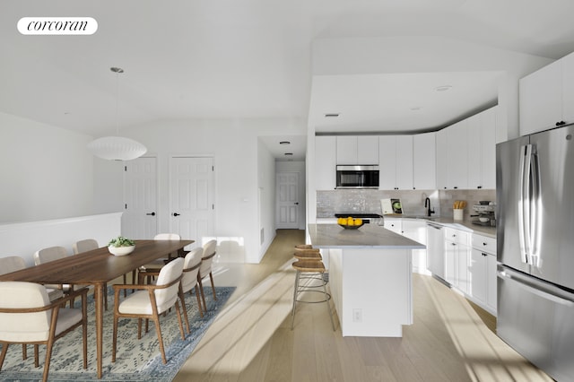 3-17 Endeavor Pl Unit C, New York City, NY 11356 - kitchen with stainless steel appliances, light wood-type flooring, tasteful backsplash, a kitchen island, and a kitchen breakfast bar