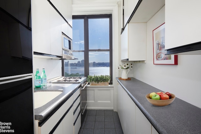 210 Riverside Dr Unit 10F, New York City, NY 10025 - kitchen featuring fridge, white range with gas stovetop, white cabinets, a water view, and dark tile patterned floors