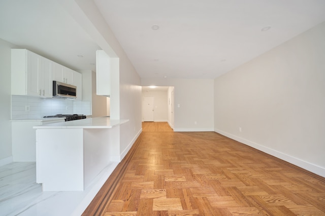 41-12 41st St Unit 2N, New York City, NY 11104 - kitchen with stainless steel microwave, tasteful backsplash, baseboards, and light countertops