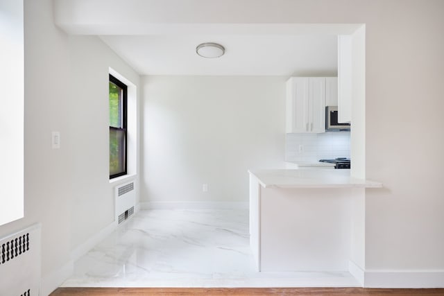 41-12 41st St Unit 2N, New York City, NY 11104 - kitchen featuring radiator, light marble finish flooring, stainless steel microwave, and white cabinetry