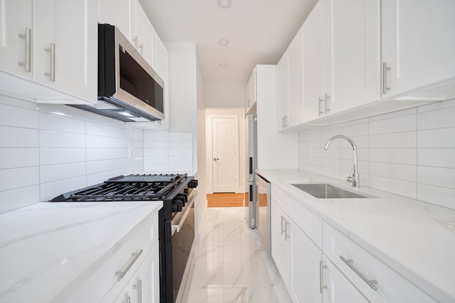 41-12 41st St Unit 2N, New York City, NY 11104 - kitchen featuring appliances with stainless steel finishes, a sink, white cabinets, and tasteful backsplash