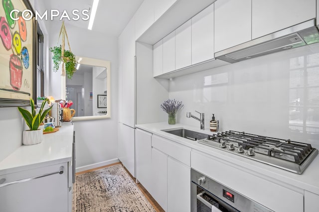 140 W 58th St Pha, Pha, New York City, NY 10019 - kitchen featuring oven, stainless steel gas cooktop, a sink, white cabinetry, and light countertops