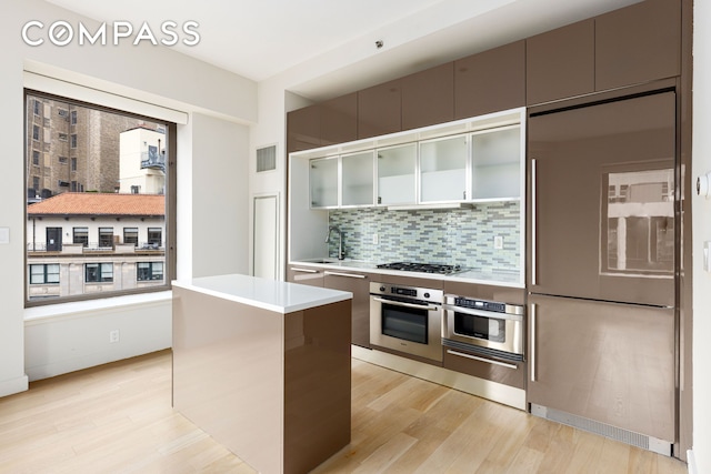 75 Wall St Unit 27F, New York City, NY 10005 - kitchen with stainless steel appliances, light wood-style flooring, backsplash, and a sink
