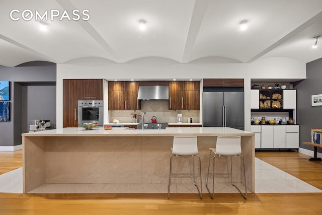 42 Ann St Unit 7, New York City, NY 10038 - kitchen with appliances with stainless steel finishes, modern cabinets, wall chimney exhaust hood, light countertops, and light wood-style flooring
