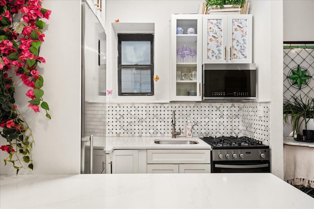 157 W 123rd St Unit 4C, New York City, NY 10027 - kitchen featuring appliances with stainless steel finishes, backsplash, glass insert cabinets, and white cabinets