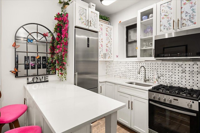 157 W 123rd St Unit 4C, New York City, NY 10027 - kitchen featuring stainless steel appliances, light countertops, a peninsula, and glass insert cabinets