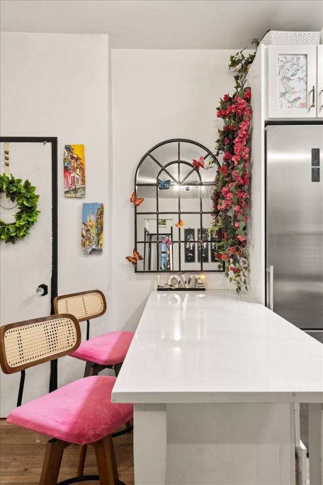 157 W 123rd St Unit 4C, New York City, NY 10027 - kitchen featuring wood finished floors, stainless steel fridge, light countertops, and a breakfast bar area