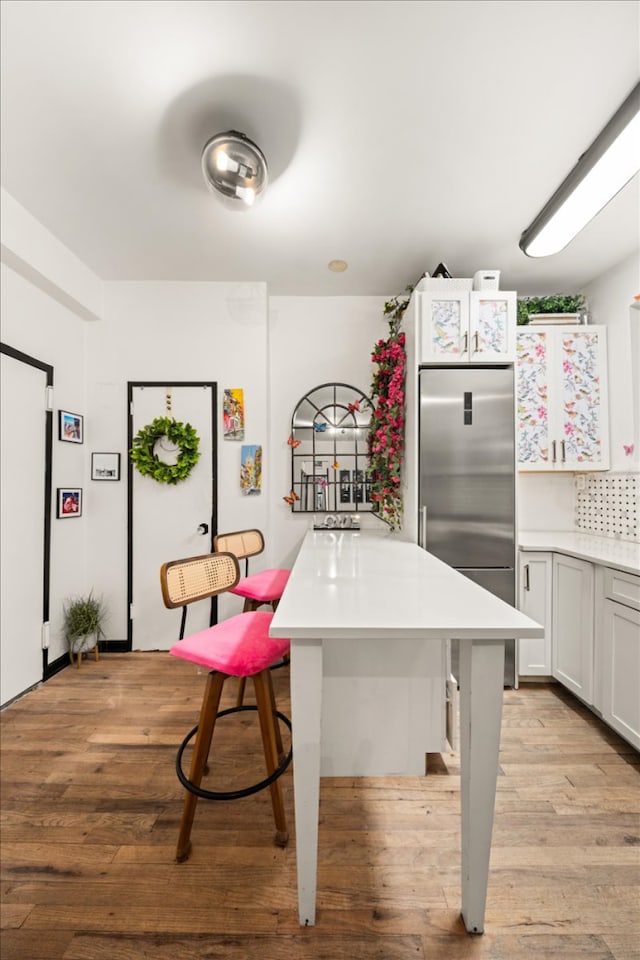 157 W 123rd St Unit 4C, New York City, NY 10027 - kitchen featuring stainless steel refrigerator, light countertops, light wood-style flooring, and a kitchen breakfast bar