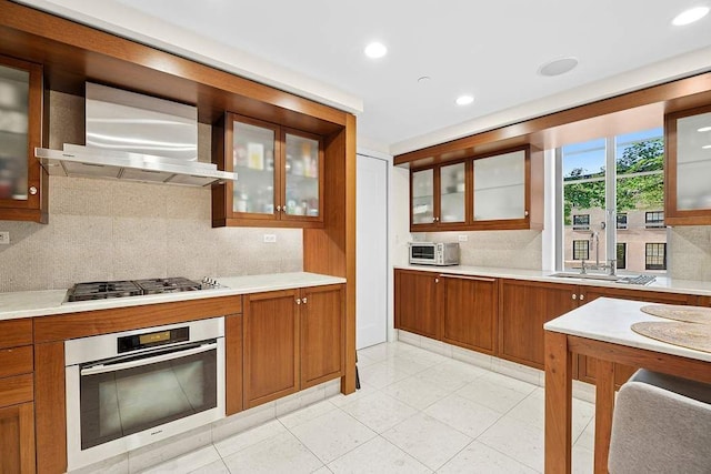 140 E 63rd St Unit 11C, New York City, NY 10065 - kitchen with stainless steel appliances, wall chimney exhaust hood, brown cabinets, light countertops, and recessed lighting