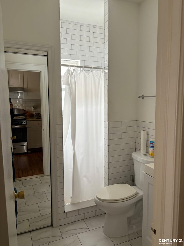 2032 W 4th St, New York City, NY 11223 - bathroom featuring tile walls, toilet, a shower with curtain, and tile patterned floors