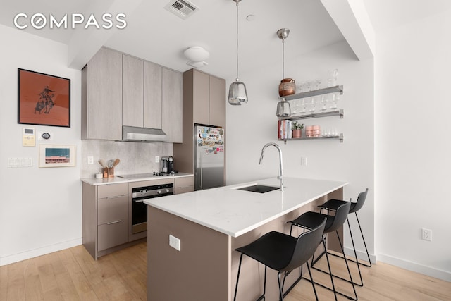 328 Central Ave Unit 1B, New York City, NY 11221 - kitchen with stainless steel appliances, a sink, a kitchen breakfast bar, under cabinet range hood, and gray cabinetry