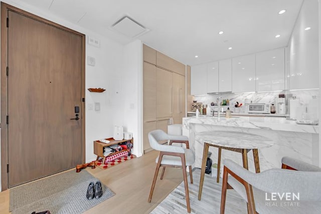 30 Riverside Blvd Unit 22F, New York City, NY 10069 - kitchen with modern cabinets, a breakfast bar area, light wood-type flooring, white cabinets, and light stone counters
