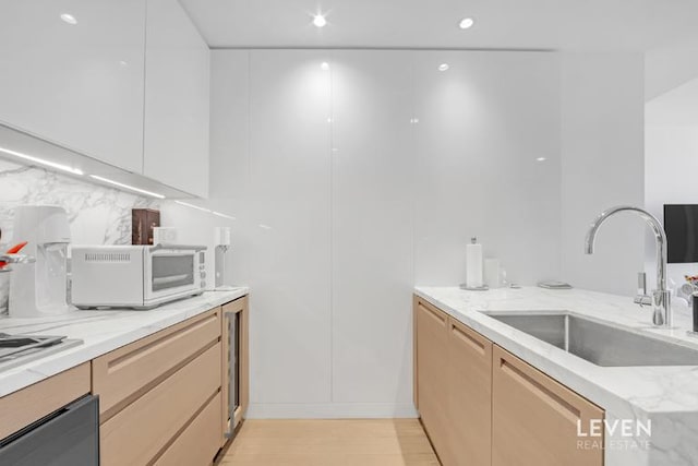 30 Riverside Blvd Unit 22F, New York City, NY 10069 - kitchen featuring light stone countertops, light wood-style floors, backsplash, white microwave, and modern cabinets