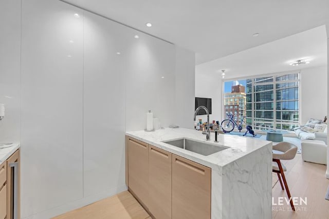 30 Riverside Blvd Unit 22F, New York City, NY 10069 - kitchen featuring a peninsula, open floor plan, light wood-type flooring, light stone counters, and a kitchen breakfast bar
