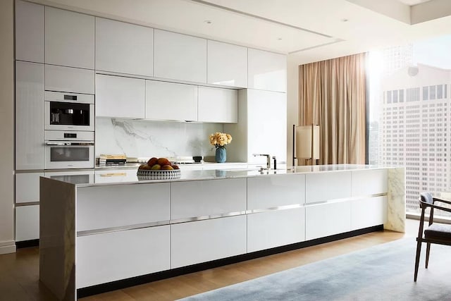 53 W 53rd St Unit 33B, New York City, NY 10019 - kitchen with tasteful backsplash, white cabinetry, a sink, and modern cabinets