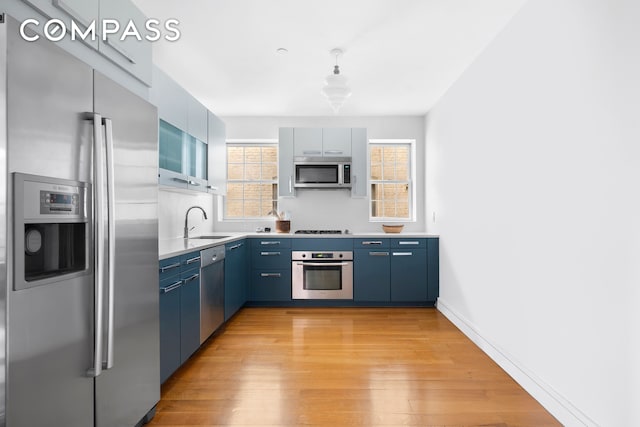 204 W 140th St Unit 4D, New York City, NY 10030 - kitchen featuring stainless steel appliances, blue cabinetry, a sink, light wood-type flooring, and light countertops