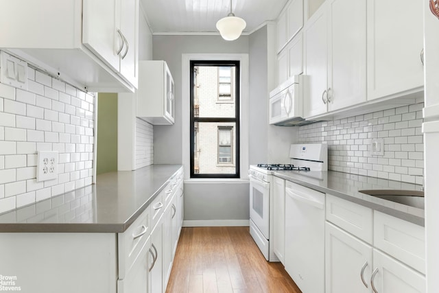 109 Seaman Ave Unit 4A, New York City, NY 10034 - kitchen with white appliances, light wood-style floors, white cabinetry, tasteful backsplash, and ornamental molding