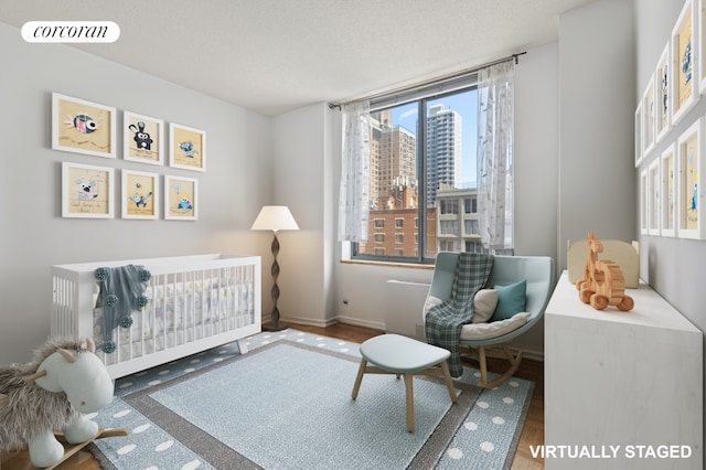 127 E 30th St Unit 11B, New York City, NY 10016 - bedroom with baseboards, wood finished floors, a textured ceiling, and a crib