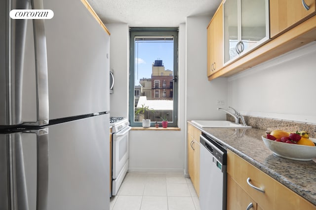 127 E 30th St Unit 11B, New York City, NY 10016 - kitchen featuring appliances with stainless steel finishes, glass insert cabinets, light tile patterned floors, and a textured ceiling