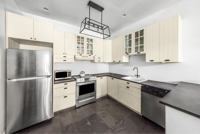 638 Monroe St, New York City, NY 11221 - kitchen with appliances with stainless steel finishes, dark countertops, cream cabinets, under cabinet range hood, and recessed lighting