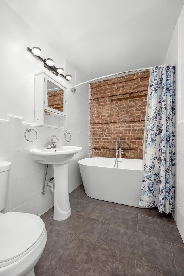 638 Monroe St, New York City, NY 11221 - full bathroom featuring a freestanding bath, a shower with shower curtain, and tile walls